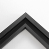 This simplistic yet modular matte black frame is designed for metal prints, acrylic prints and dry mounts. This smart design features a minimalist stepped profile that serves as a floater frame or a standard picture frame.

For the floating effect, the print can be attached on top of the inner step of the frame, without sacrificing the artwork edges.

This frame can also be used as standard picture frame. The lowered center paired with slightly raised outer lip creates a frame within a frame effect. However, due to the inner most lip of the frame, a fraction of the artwork will be hidden. But, this can be avoided with a linen liner combo.